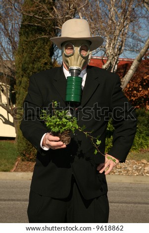 an environmentally friendly business man in a nice suit, and a Gasmask holds a green plant to save the earth from Global Warming