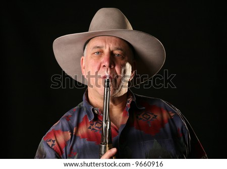 A cowboy blows smoke from the barrel of a freshly fired Colt Navy 44 caliber black powder revolver