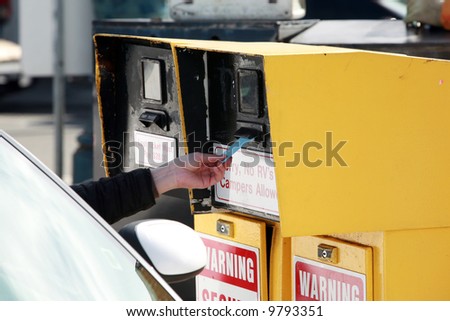 a human hand reaches for a parking ticket at a self service parking lot