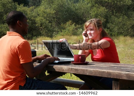 a young woman attempts to demand attention from a man working on his laptop computer outside