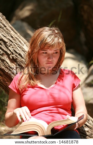 a young woman reads a book outside