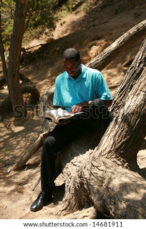 a young man reads a book outside
