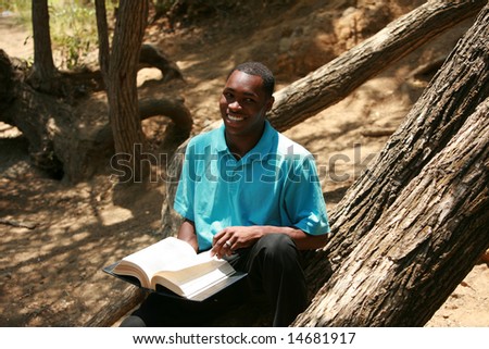 a young man reads a book outside