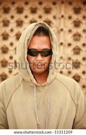 a male model wears a green hooded sweat shirt and sunglasses to hide from the paparazzi