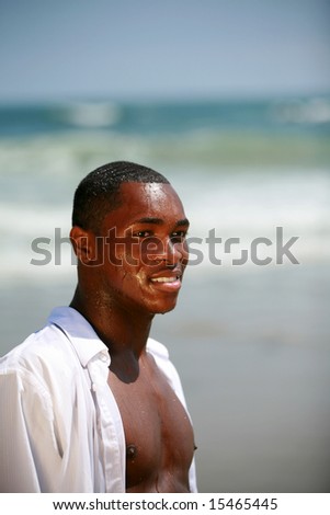a handsome african american male model is shocked at how cold, cold water is from a bottle on a beautiful summer day