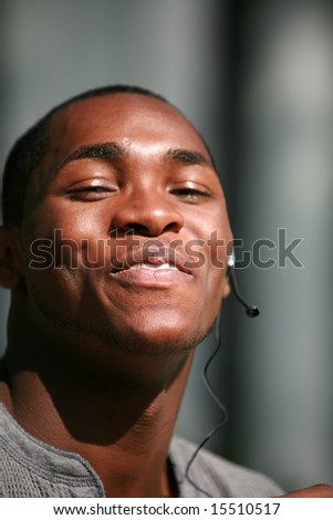 a handsome black guy talks on his hands free cellular phone headset