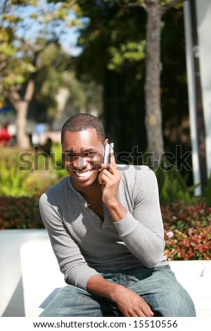 a handsome african american man laughs and talks on his cell phone