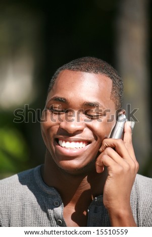a handsome african american man laughs and talks on his cell phone