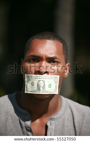 a young man wears a dollar bill taped over his mouth in protest against inflation and the rising cost of goods and services