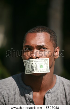 a young man wears a dollar bill taped over his mouth in protest against inflation and the rising cost of goods and services