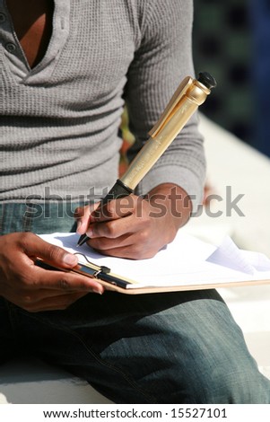 a young man takes notes on a sheet of paper with a giant pen