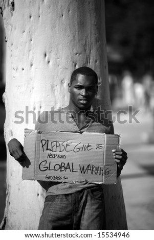 a man asks for donations to help stop Global Warming with his cardboard sign in black and white