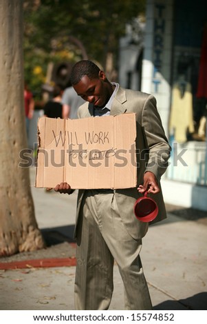 a thursty african american male model stands on a city street with a cardboard sign that reads \