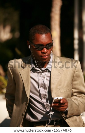 a well dressed african american Male Model listens to his personal digital music player