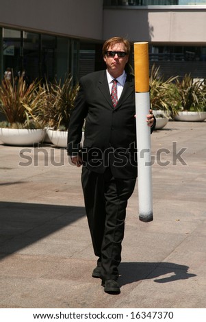 Anti-Smoking Concepts. A business man in a suit holds a Giant Cigarette,  with a book of matches