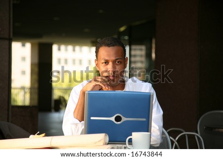 a business man works from his office at an outdoor coffee shop with his laptop and wireless internet connection