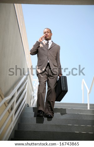 a business man talks on his cell phone as he walks down stairs