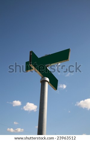 a blank green street sign against a blue sky outside