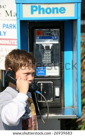 a young boy uses a public pay phone