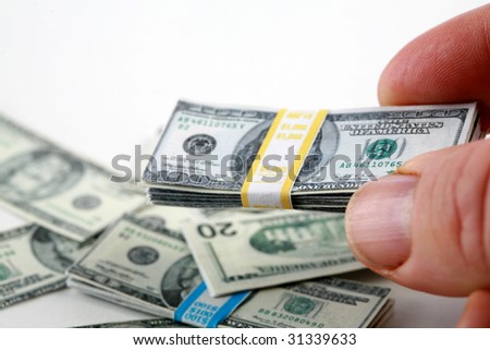 a hand holds miniature money representing the world financial crisis isolated on white