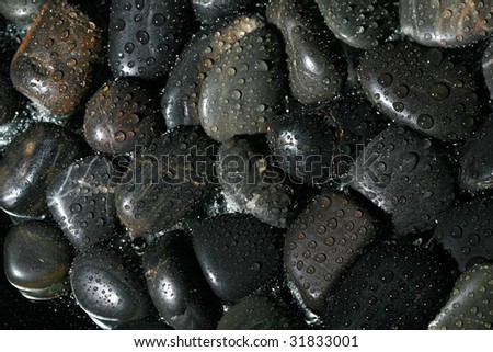 Low Key Studio Shot of black shiny rocks with water-drops on them  Isolated on black