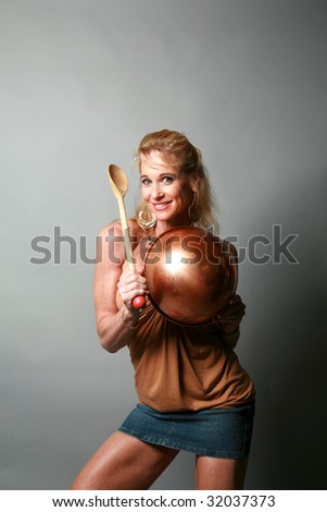 a woman plays around with her copper bowl and wooden spoon  isolated on grey