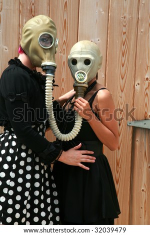 two young women wear gas masks connected to each other for a unique photograph