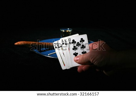 Low Key Studio Shot of a blue enamled plate with a shot of Tequila, a lime segment, pinch of salt, a good cigar and a match and a winning hand of poker isolated on black