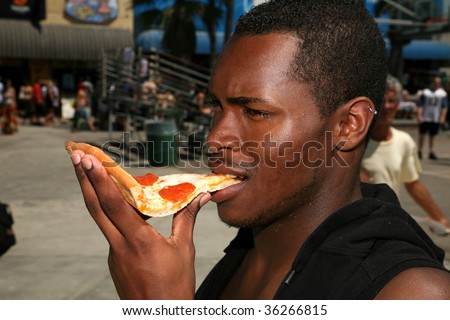 a guy eats pizza outside