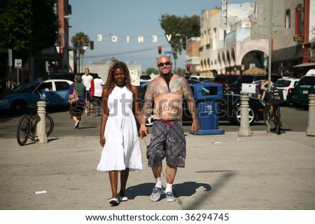 a unique couple walk hand in hand on a hot summer day in \