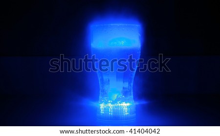 time laps exposure of a neon blue glowing drink cup bubbling with dry ice and fog in a pitch black room