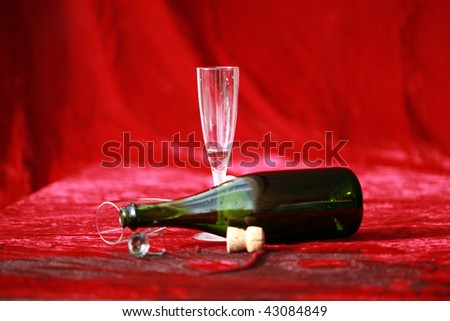 empty champagne glasses and bottle lay on wet red velvet after the party
