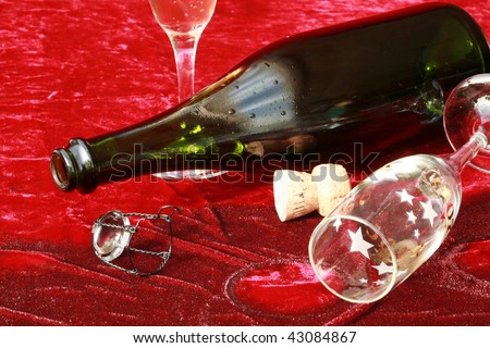 empty champagne glasses and bottle lay on wet red velvet after the party