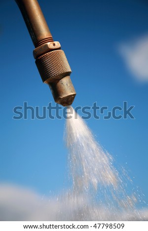 outside shower spray nozzle against a blue sky with flowing water