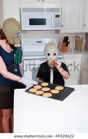 a mother and son enjoy peanut butter cookies in their kitchen while wearing gas masks in a post nuclear winter future