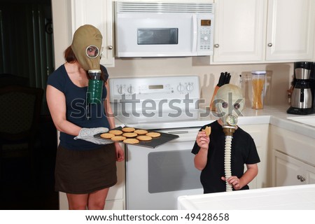 a mother and son enjoy peanut butter cookies in their kitchen while wearing gas masks in a post nuclear winter future