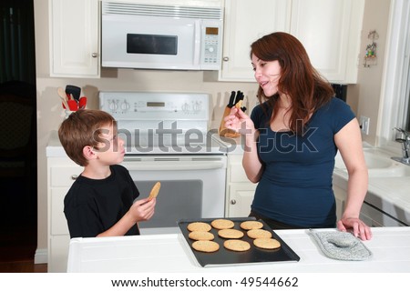 a mother and son enjoy hot fresh baked cookies after school in the kitchen