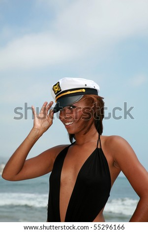 a beautiful young african american woman wears a sea captains hat while enjoying a day at the beach