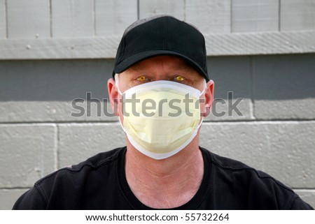 a man wears a yellow medical paper mask as he looks around to stay safe from any air born illness