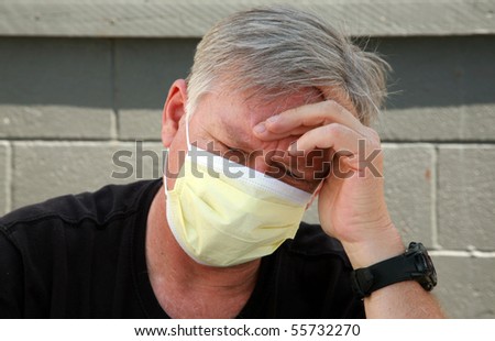a man wears a yellow medical paper mask as he worries about how to stay safe from any air born illness