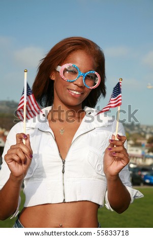 a beautiful african american woman wears american flag glasses and waves american flags for the 4th of july