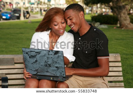 a young african american couple enjoy using a laptop computer outside