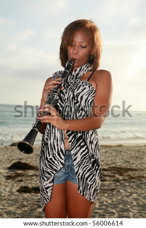 a young african american woman plays her clarinet outside at the beach for all to hear and enjoy