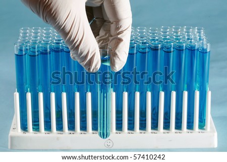 a science or medical research scientist holds and examines a test tube filled with a blue liquid