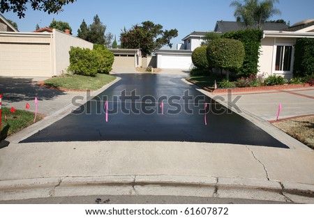 fresh hot tar aka black top on an ashphalt driveway in a neighborhood