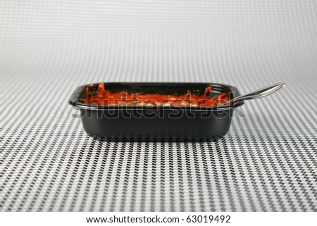 Hot fresh from the Microwave oven a Lasagna tv dinner sits on a black and white background waiting to be eaten by a hungry person about to watch their favorite tv program