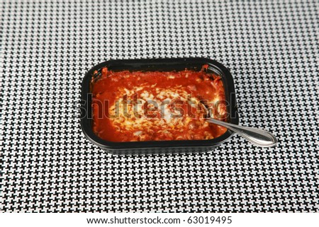 Hot fresh from the Microwave oven a Lasagna tv dinner sits on a black and white background waiting to be eaten by a hungry person about to watch their favorite tv program