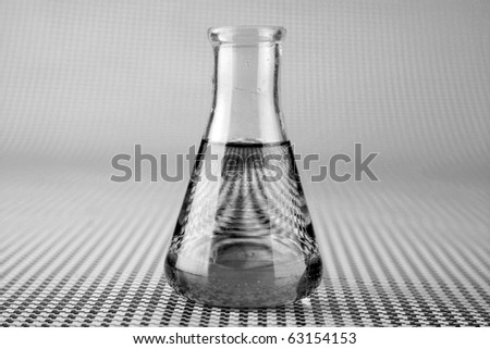 a chemist or medical research scientist adds chemicals to a erlenmeyer flask for a violent chemical reaction on a black and white background