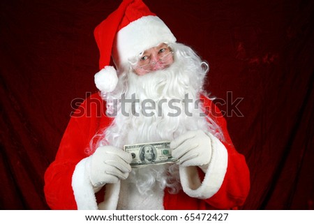 Santa Claus hold money in preparation to give to you for christmas or the concept of the high cost of christmas against a red velvet background