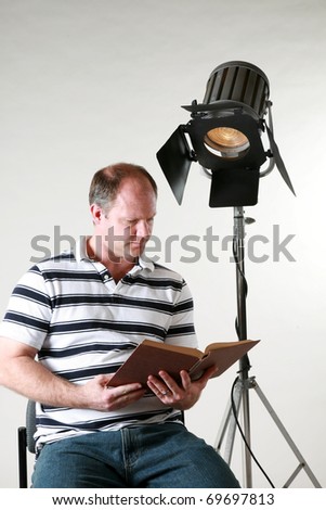 a man enjoys a good book by the light from an antique movie studio spot light